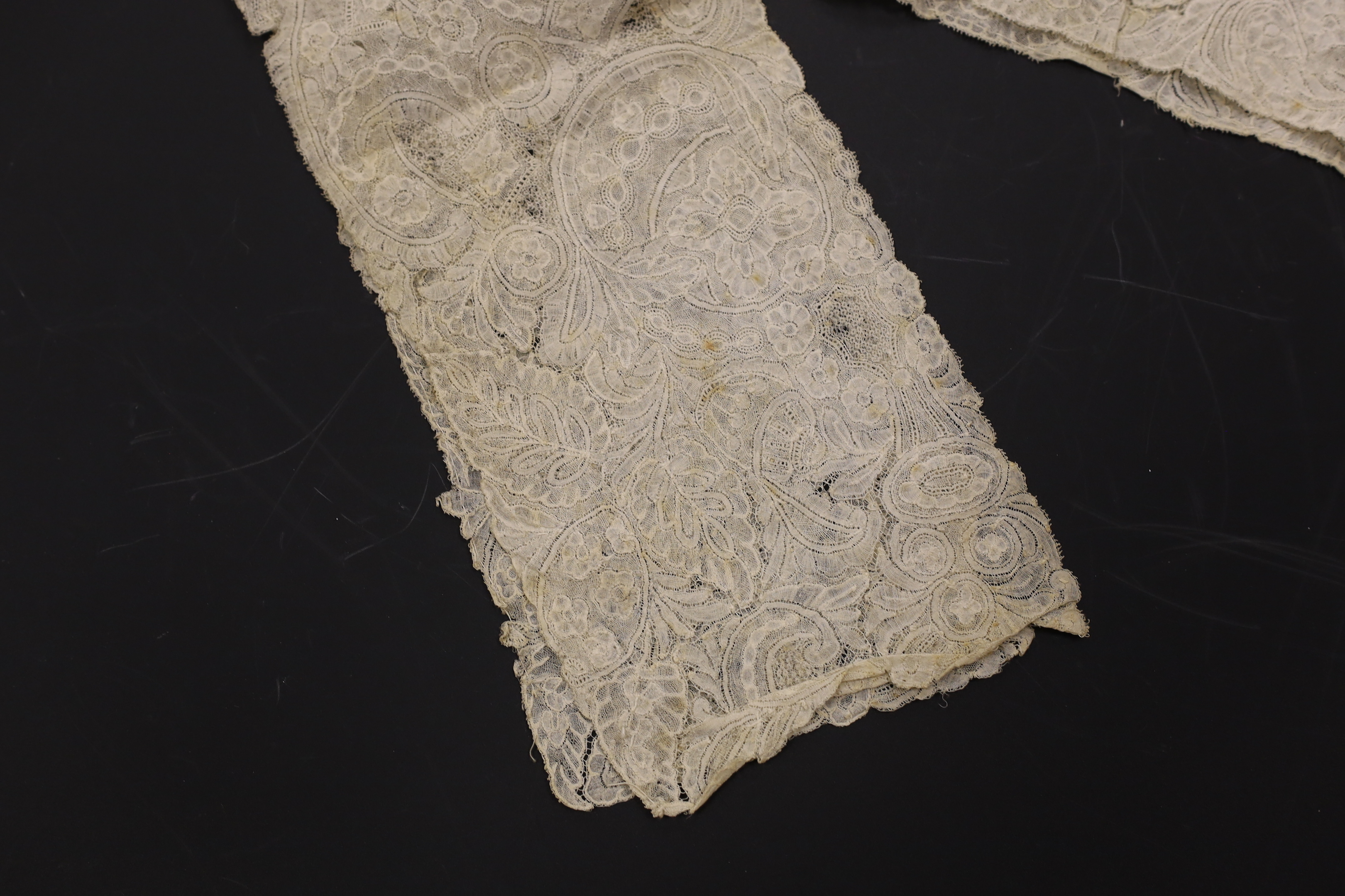 An early 18th century Hollie point insertion baby’s linen vest, three baby bonnets with Hollie point insertions and an early 18th century pair of Flemish bobbin lace lappets, a partly finished needlepoint length of lace,